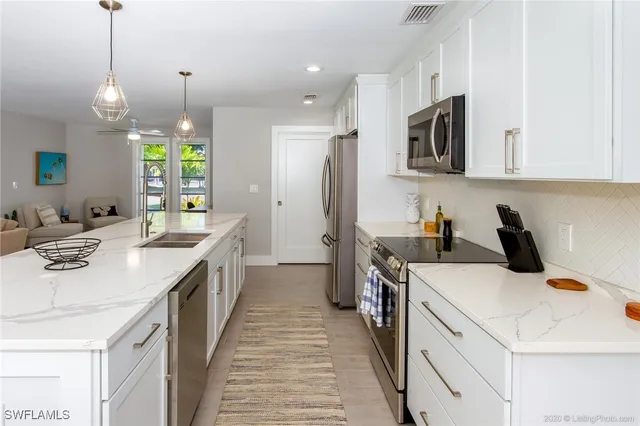 a kitchen that has a lot of white cabinets and stainless steel appliances