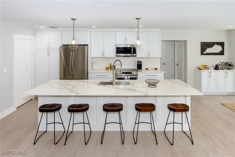 a kitchen with stainless steel appliances granite countertop a table chairs stove and refrigerator