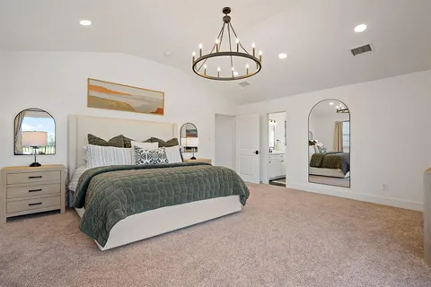 a spacious bedroom with a bed and a chandelier