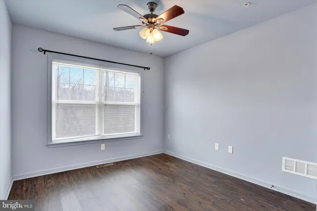 a view of an empty room with window and wooden floor