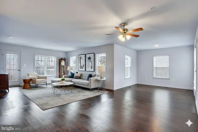a living room with couches and kitchen view with wooden floor