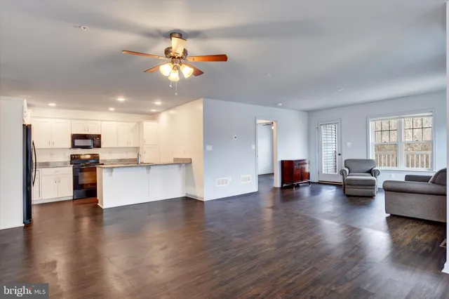 a view of a living room a kitchen with furniture wooden floor and windows
