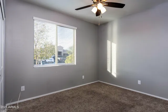 an empty room with ceiling fan and window