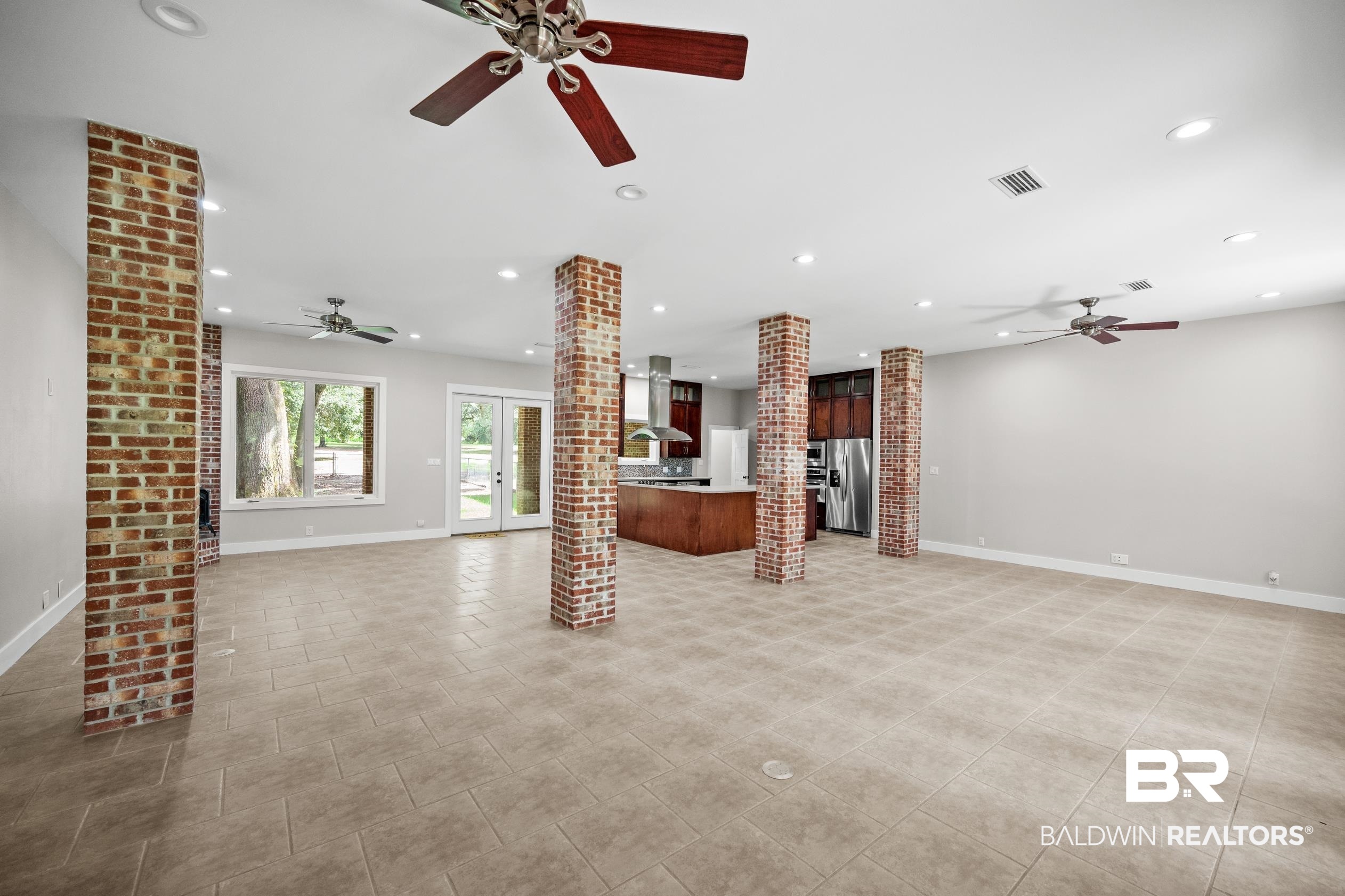 15031 Timber Ridge Drive Loxley, AL 36551 - Photo 16 of 43 Unfurnished living room with brick wall, light tile patterned floors, decorative columns, and ceiling fan
