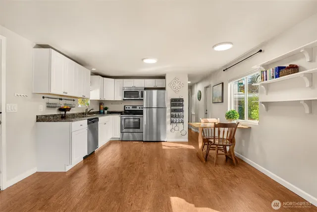 a kitchen with stainless steel appliances wooden floor and a refrigerator