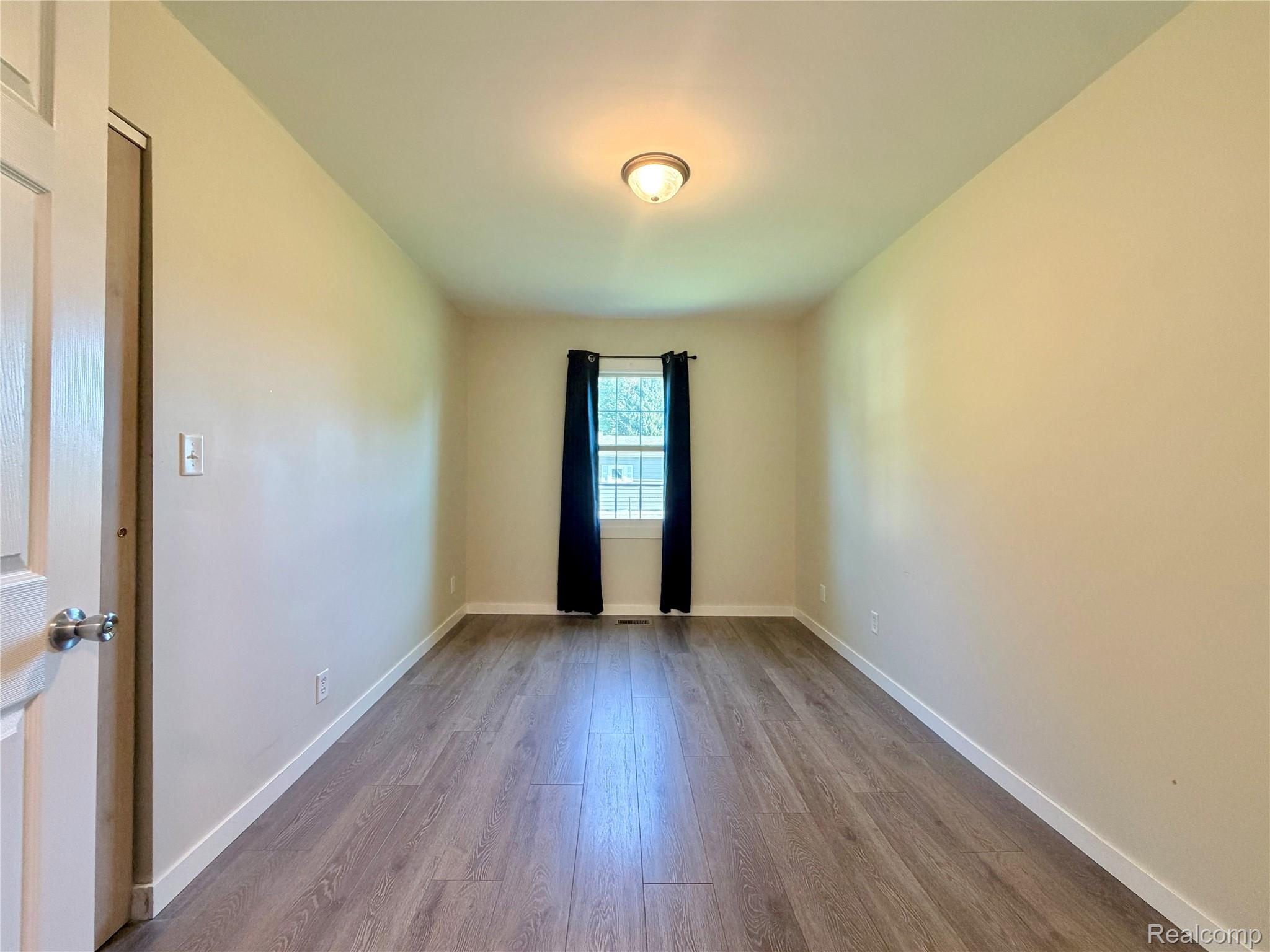 1295 Allen Road Smiths Creek, MI 48074 - Photo 21 of 28 Spacious room featuring wood-finish flooring, light-toned walls, and a window with dark curtains