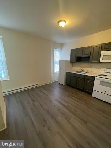a view of kitchen with stainless steel appliances wooden floor and large window