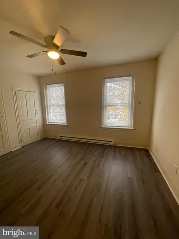 an empty room with wooden floor fan and windows