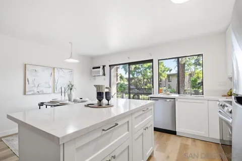 a kitchen with kitchen island a sink a stove and white cabinets with wooden floor