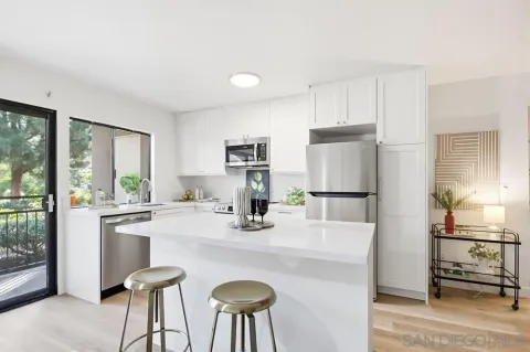 a kitchen with kitchen island a stove a refrigerator a sink a dining table and chairs