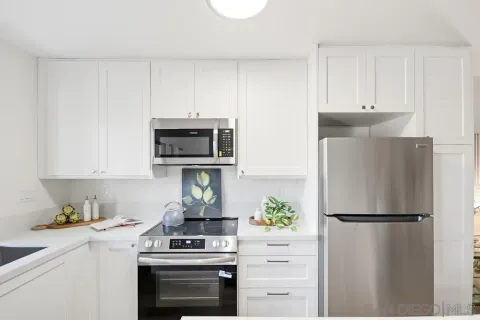 a kitchen with stainless steel appliances a refrigerator a stove and white cabinets