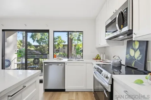 a kitchen with stainless steel appliances a sink a stove and a wooden floor