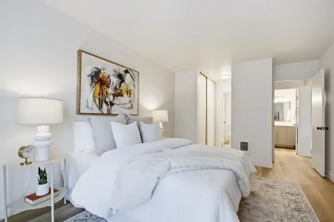 a spacious bedroom with a bed and painting on the wall