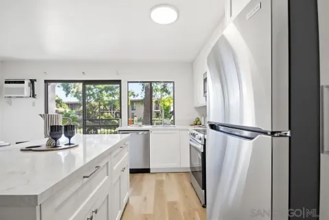 a kitchen with a refrigerator a sink and white cabinets next to a window