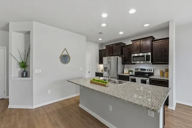 a kitchen with stainless steel appliances microwave stove refrigerator and wooden floor