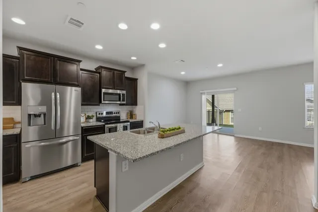 a kitchen with granite countertop a refrigerator and a stove top oven