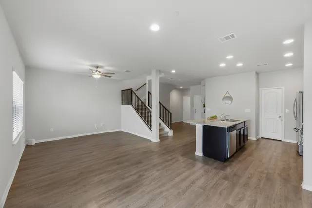 an empty room with wooden floor and a ceiling fan