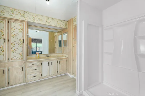 a spacious bathroom with a shower a sink and a mirror