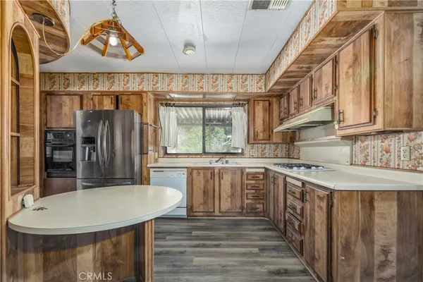 a kitchen with stainless steel appliances granite countertop a stove a sink dishwasher and a refrigerator with wooden floor