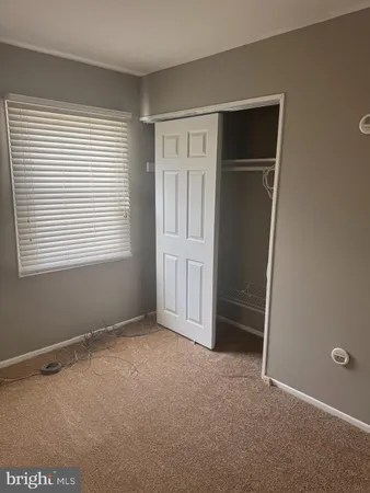 a view of an empty room with closet and a window