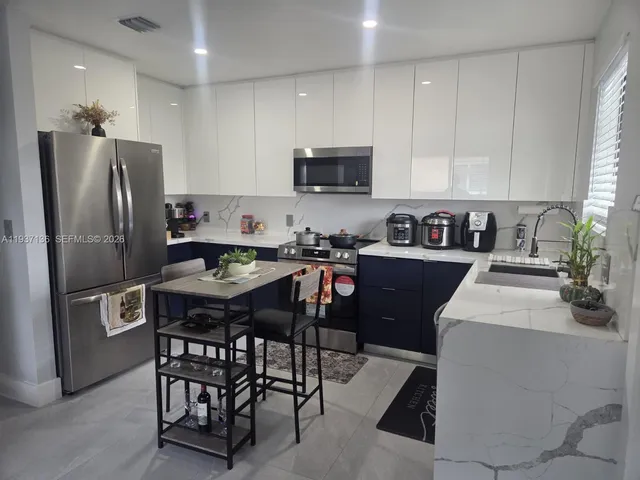 a kitchen with stainless steel appliances a table chairs refrigerator and a sink