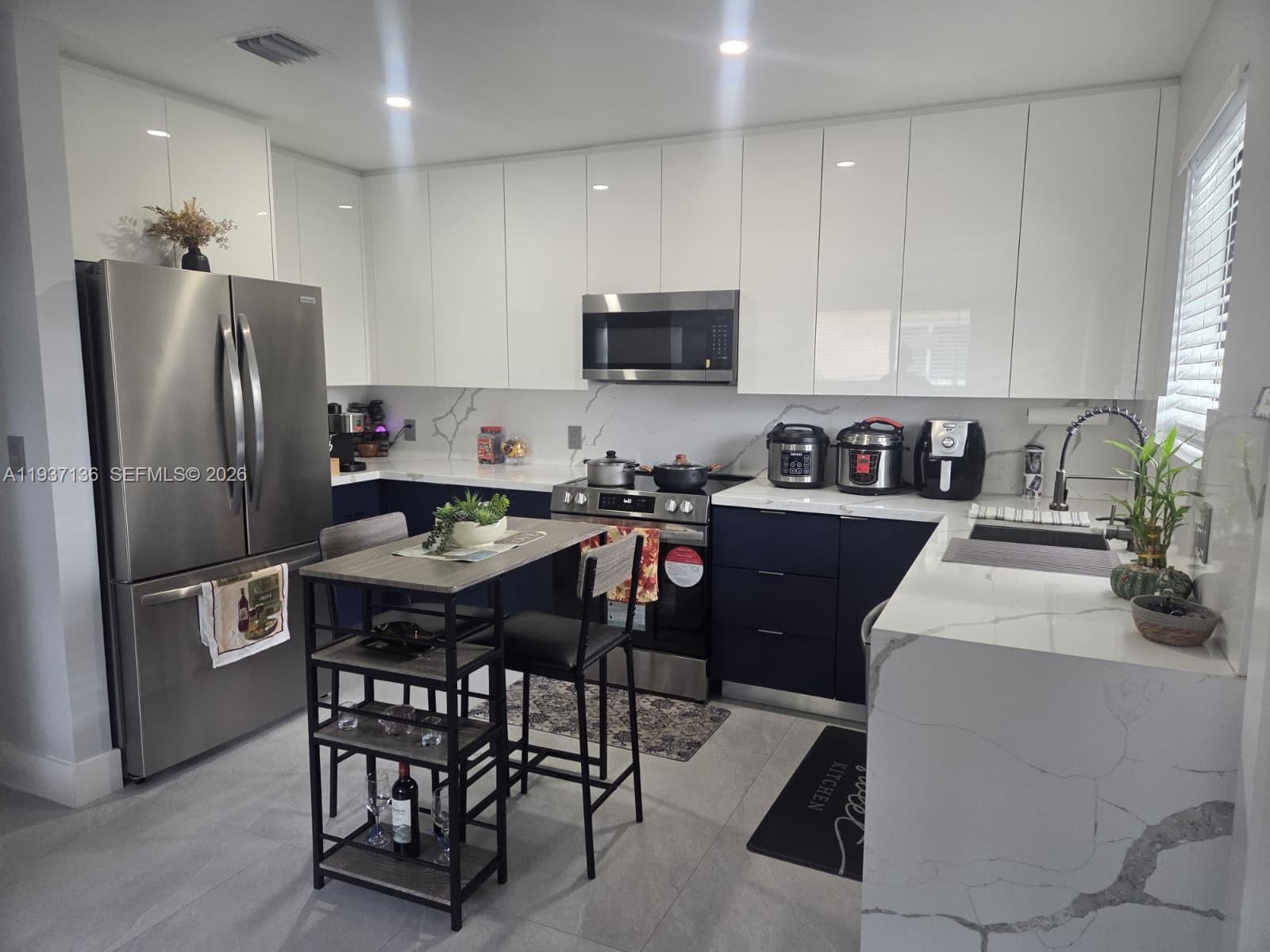 a kitchen with stainless steel appliances a table chairs refrigerator and a sink
