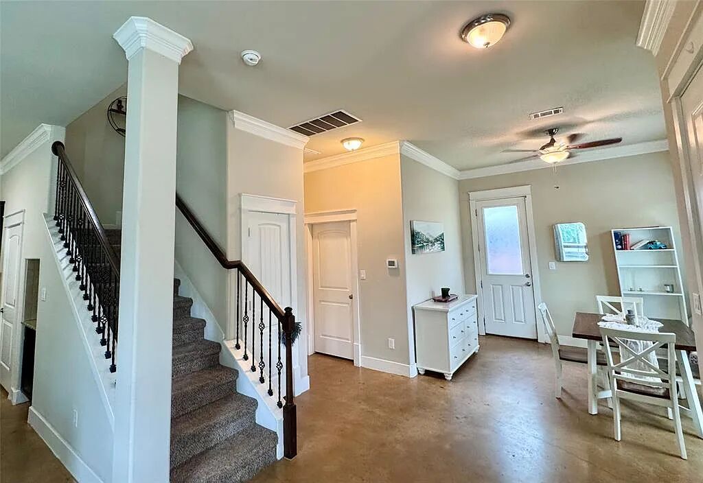 4420 Red River Street, Unit B Austin, TX 78751 - Photo 3 of 11 A well-lit interior features a carpeted staircase with an elegant wrought iron railing, complemented by crown molding throughout.