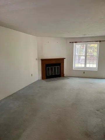 an empty room with a fireplace and windows