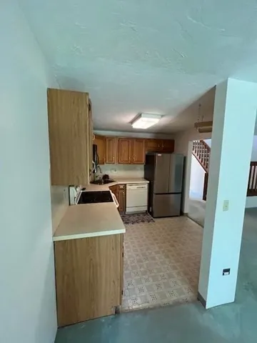 a kitchen with a refrigerator sink and wooden cabinets