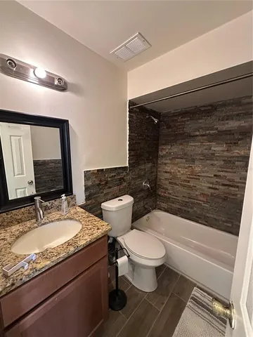 a bathroom with a granite countertop toilet sink and mirror
