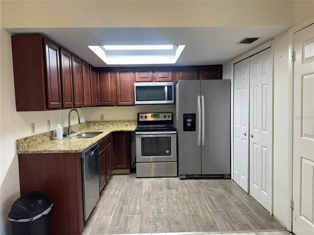 a kitchen with stainless steel appliances granite countertop a refrigerator and a stove top oven