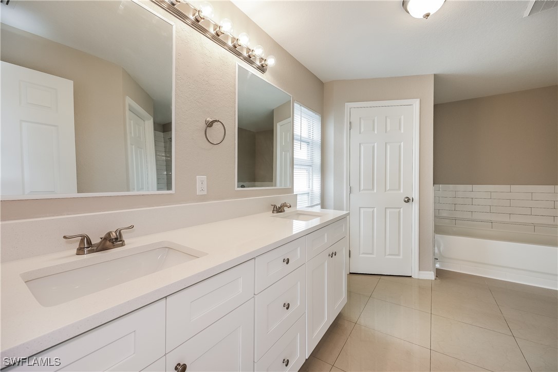 404 Willowbrook Drive Lehigh Acres, FL 33972 - Photo 11 of 16 a spacious bathroom with a double vanity sink mirror and a bathtub