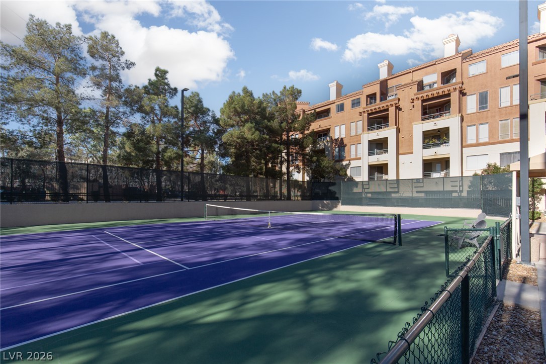 210 East Flamingo Road, Unit 117 Las Vegas, NV 89169 - Photo 21 of 24 An outdoor tennis court sits adjacent to a multi-story residential building under a partly cloudy sky.