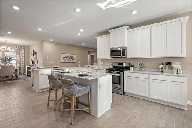 a kitchen with stainless steel appliances granite countertop a stove top oven a sink a stove a dining table and chairs