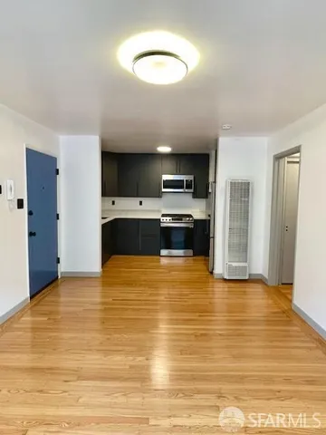 a view of kitchen and empty room with wooden floor