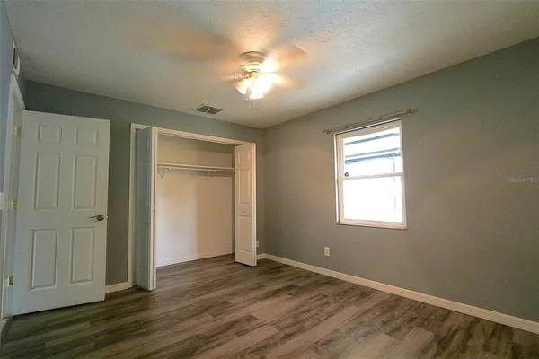 a view of empty room with wooden floor and fan