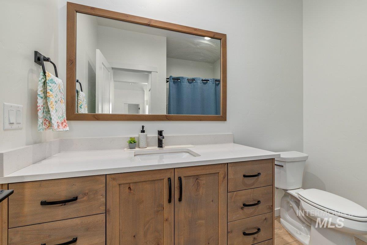 1380 West Chilitna Street Meridian, ID 83642 - Photo 33 of 50 Bathroom vanity featuring wood-finish cabinetry with black hardware, a white countertop, and an undermount sink