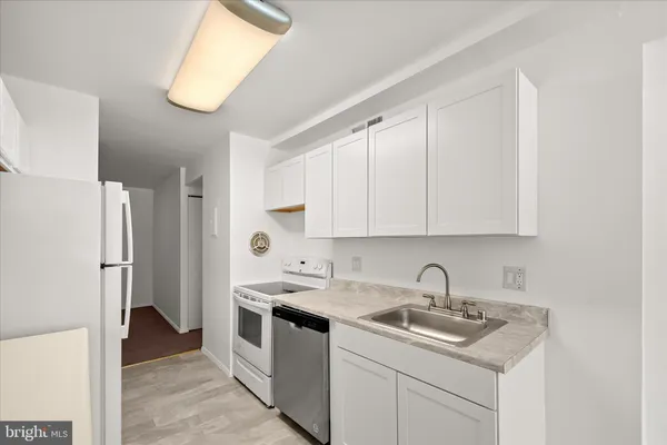 a kitchen with white cabinets and window