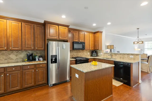 a kitchen with stainless steel appliances granite countertop a refrigerator a sink dishwasher a stove and white countertops with wooden floor