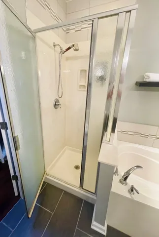 a bathroom with a glass door shower and vanity