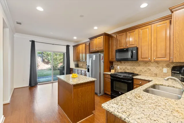 a kitchen with stainless steel appliances granite countertop a sink stove refrigerator and a window