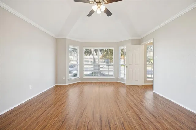 an empty room with wooden floor chandelier fan and windows