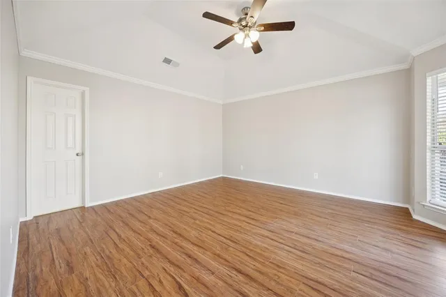 a view of empty room with wooden floor and fan