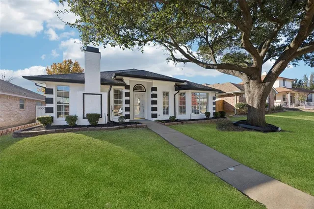 a front view of a house with a garden and trees