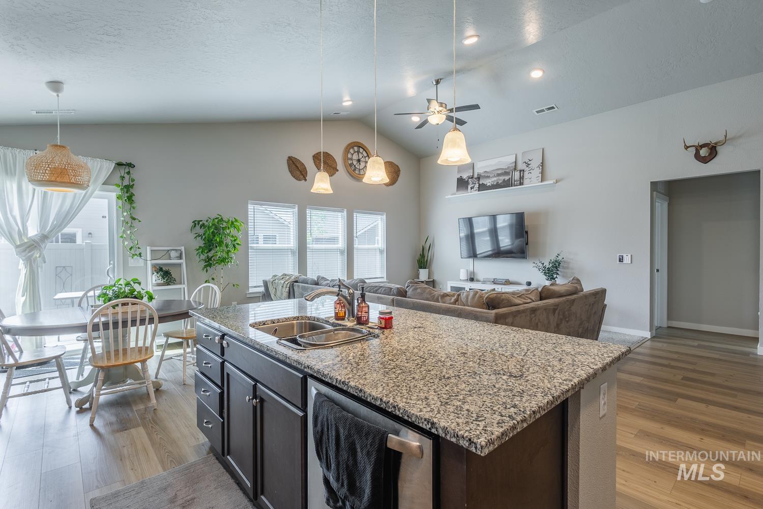 12623 Shadow Peak Street Caldwell, ID 83607 - Photo 17 of 50 Kitchen island featuring a granite-finish countertop, undermount stainless steel sink, and dark cabinetry