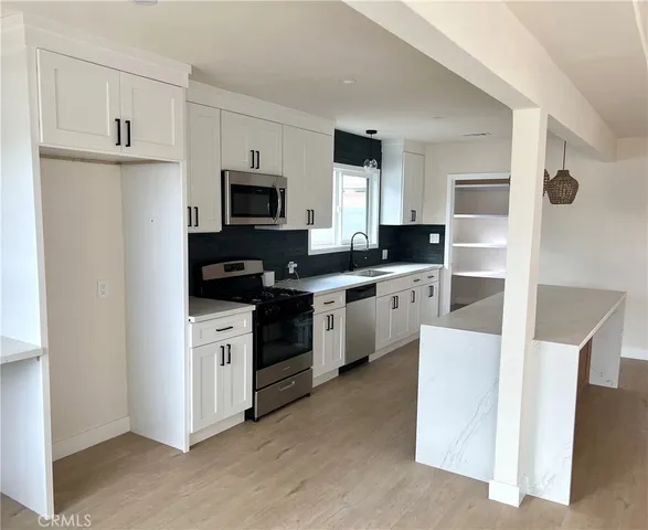 a kitchen with white cabinets and appliances