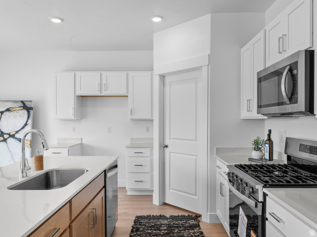 738 West 2840 South, Unit 6 Nibley, UT 84321 - Photo 13 of 23 Modern kitchen featuring white shaker cabinetry, light-toned countertops, a stainless steel gas range, and a built-in microwave
