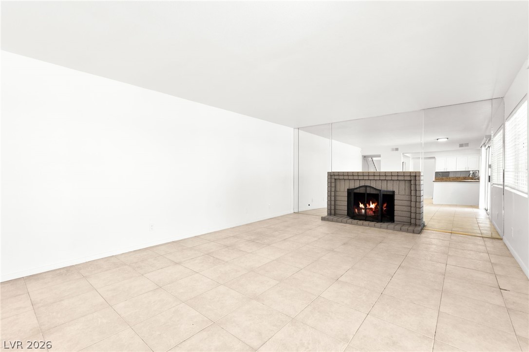 4430 Cranbrook Way Las Vegas, NV 89103 - Photo 18 of 50 A well-lit living area features tiled flooring and a prominent brick fireplace, offering a cozy ambiance.