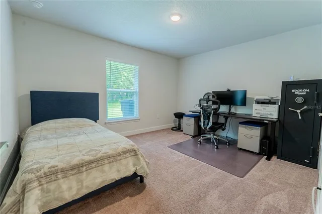 a bedroom with a bed table chair and a window
