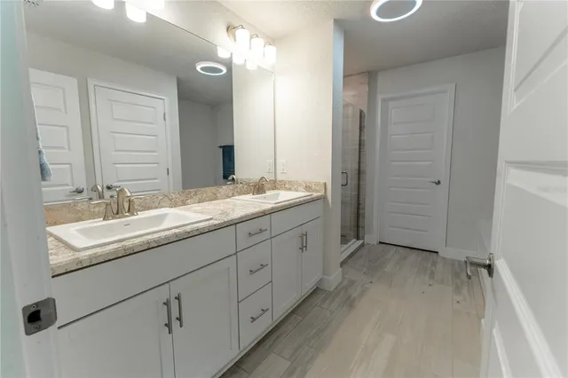a bathroom with a double vanity sink and mirror with shower